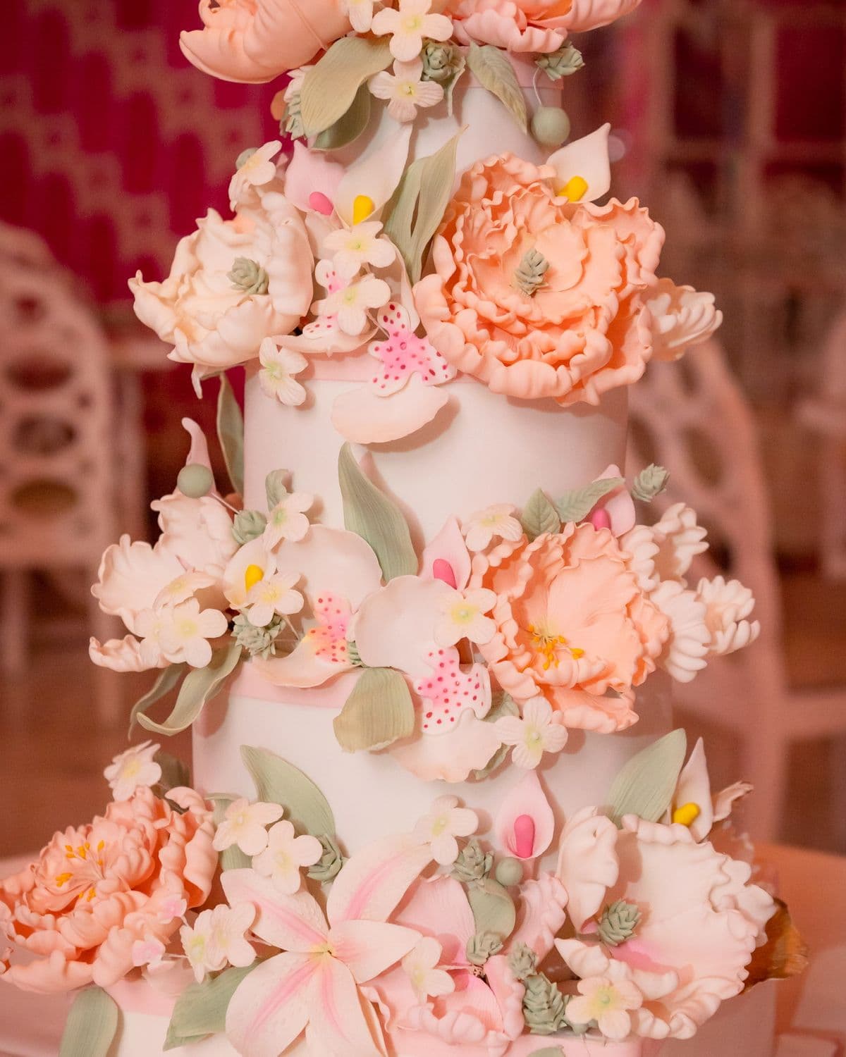 Four-tier ivory wedding cake covered in hand-made blush sugar peonies and ranunculus