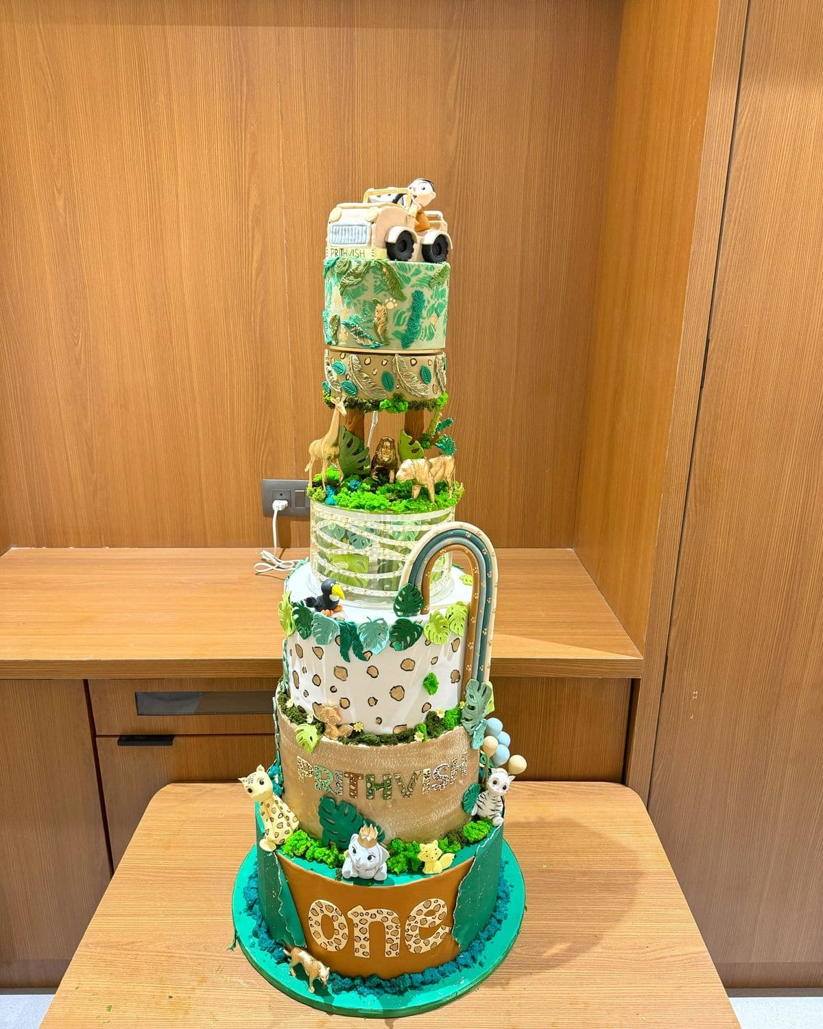 Three-tier jungle-themed first birthday cake with hand-modelled animals on each tier