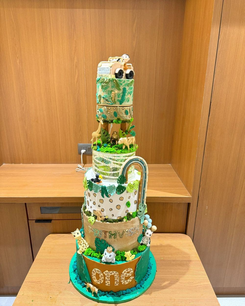 Jungle-themed tiered first birthday cake with modelled animals