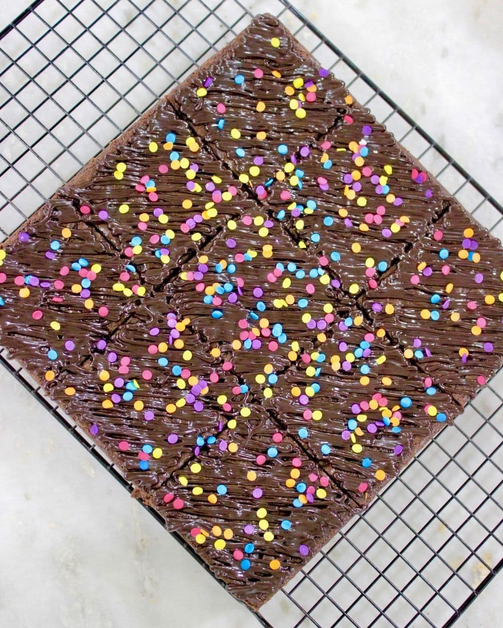 Chocolate brownie topped with coloured sprinkles on a cooling rack