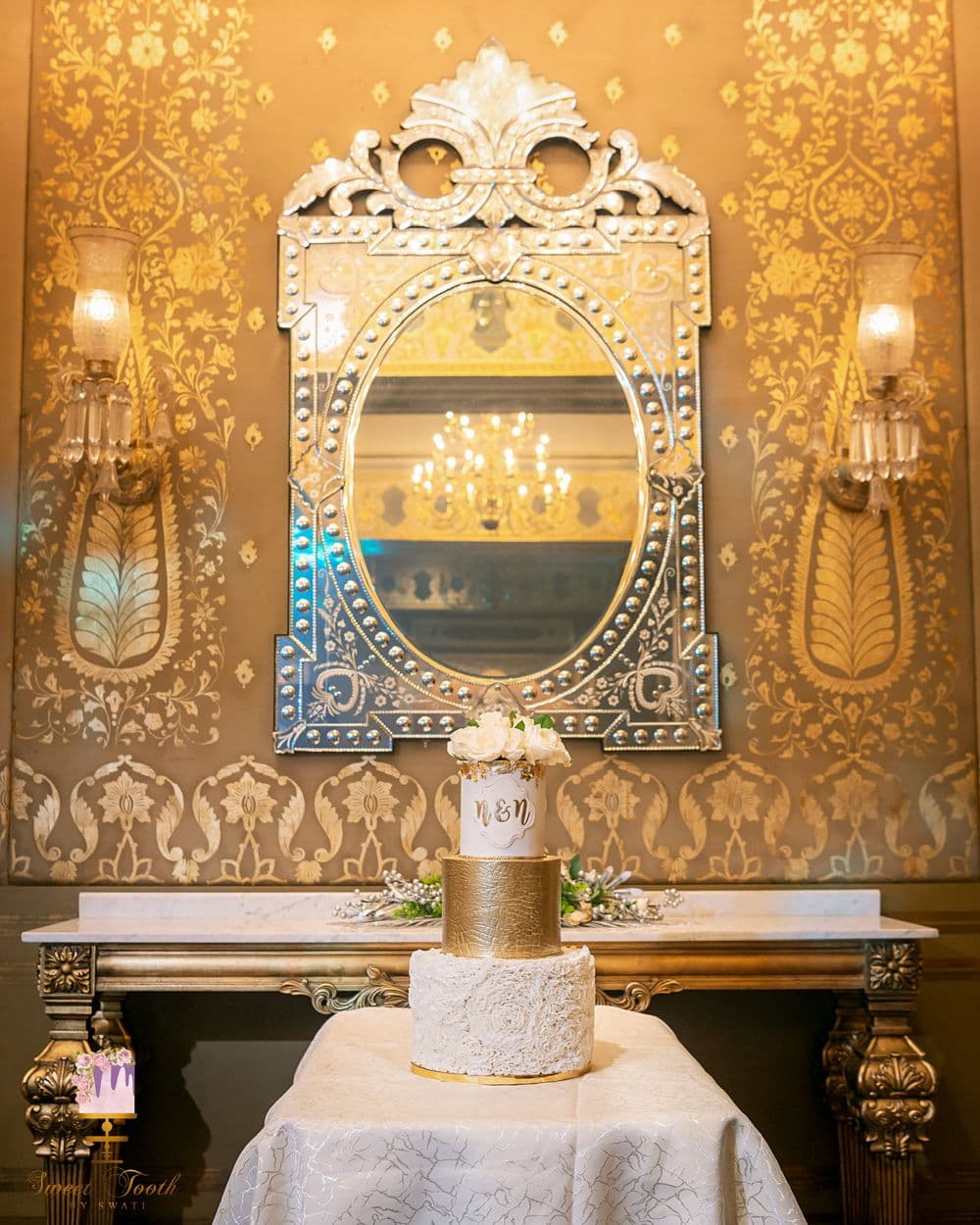 Tiered ivory wedding cake on a gilded table