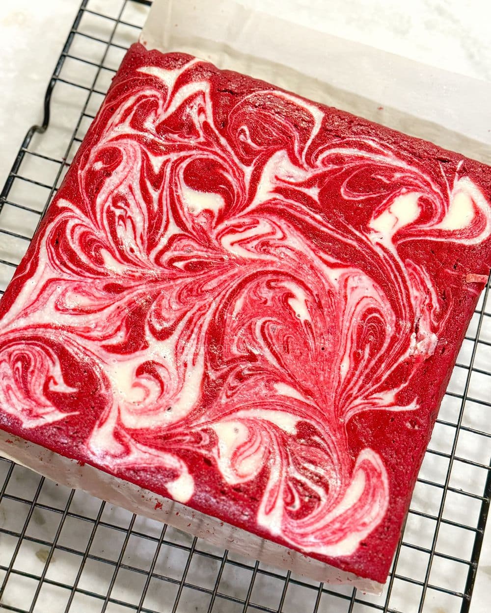 Red velvet traybake with a cream cheese swirl on a cooling rack